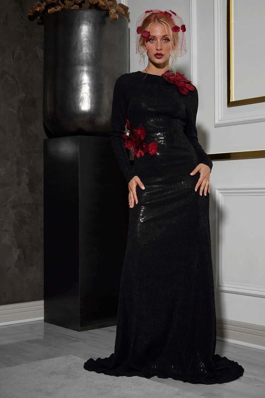 Model wearing the Calliandra Maxi Dress, a backless dress with red feathers, showcasing elegance and glamour.