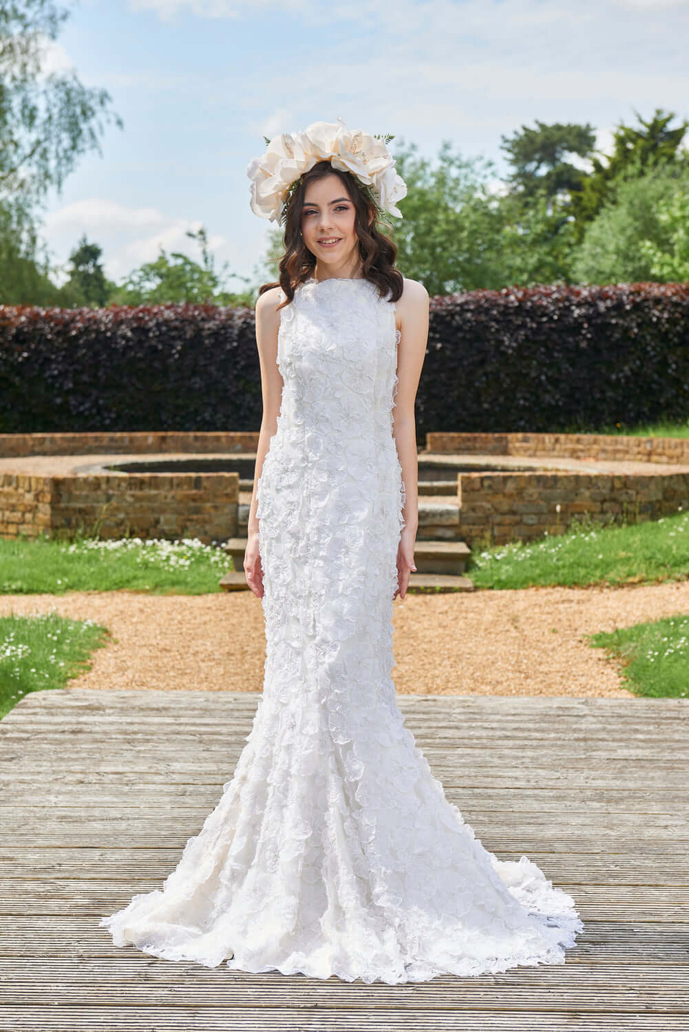 Myriss Wedding Dress featuring 3D floral appliques, model wearing gown in outdoor setting with flower crown.