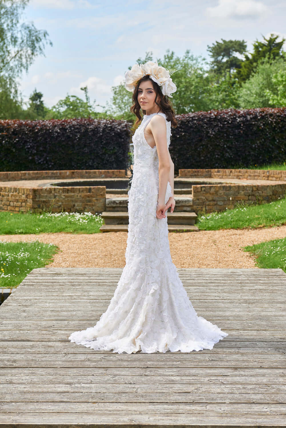 Myriss Wedding Dress: 3D Floral Applique Gown on a model outdoors, showcasing romantic bridal elegance.