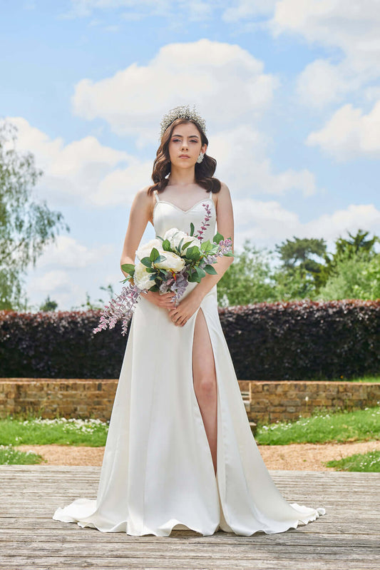 Daneriss Wedding Dress on a bride holding a bouquet, featuring a floor-sweeping train and elegant design.