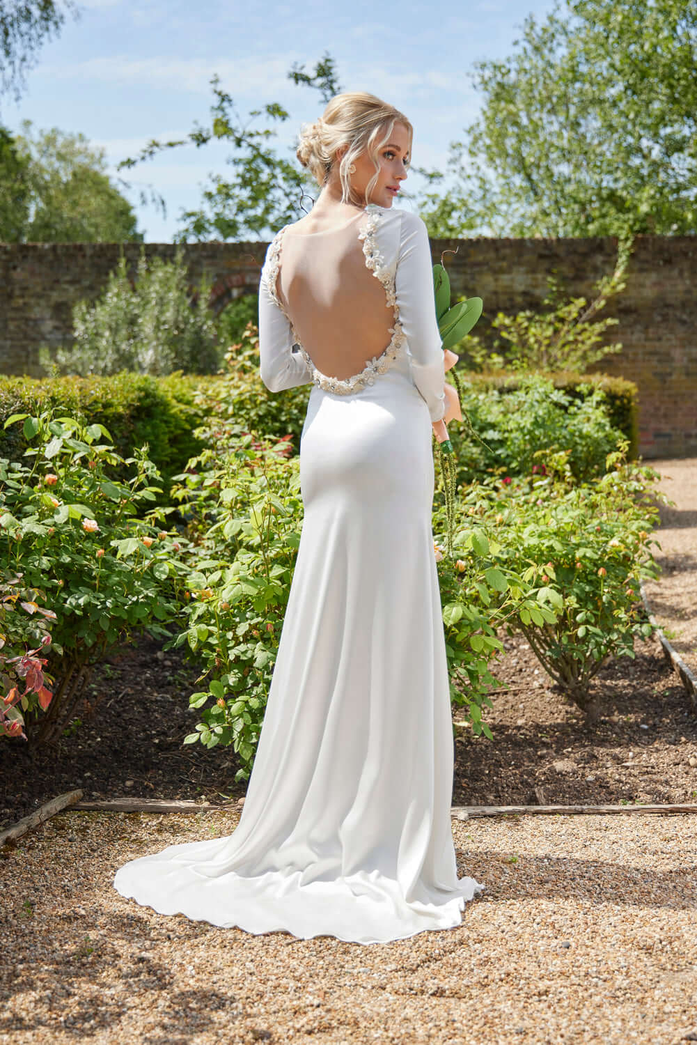 Kassia Wedding Dress - Elegant silk gown with open back, showcasing timeless style in a beautiful garden setting.