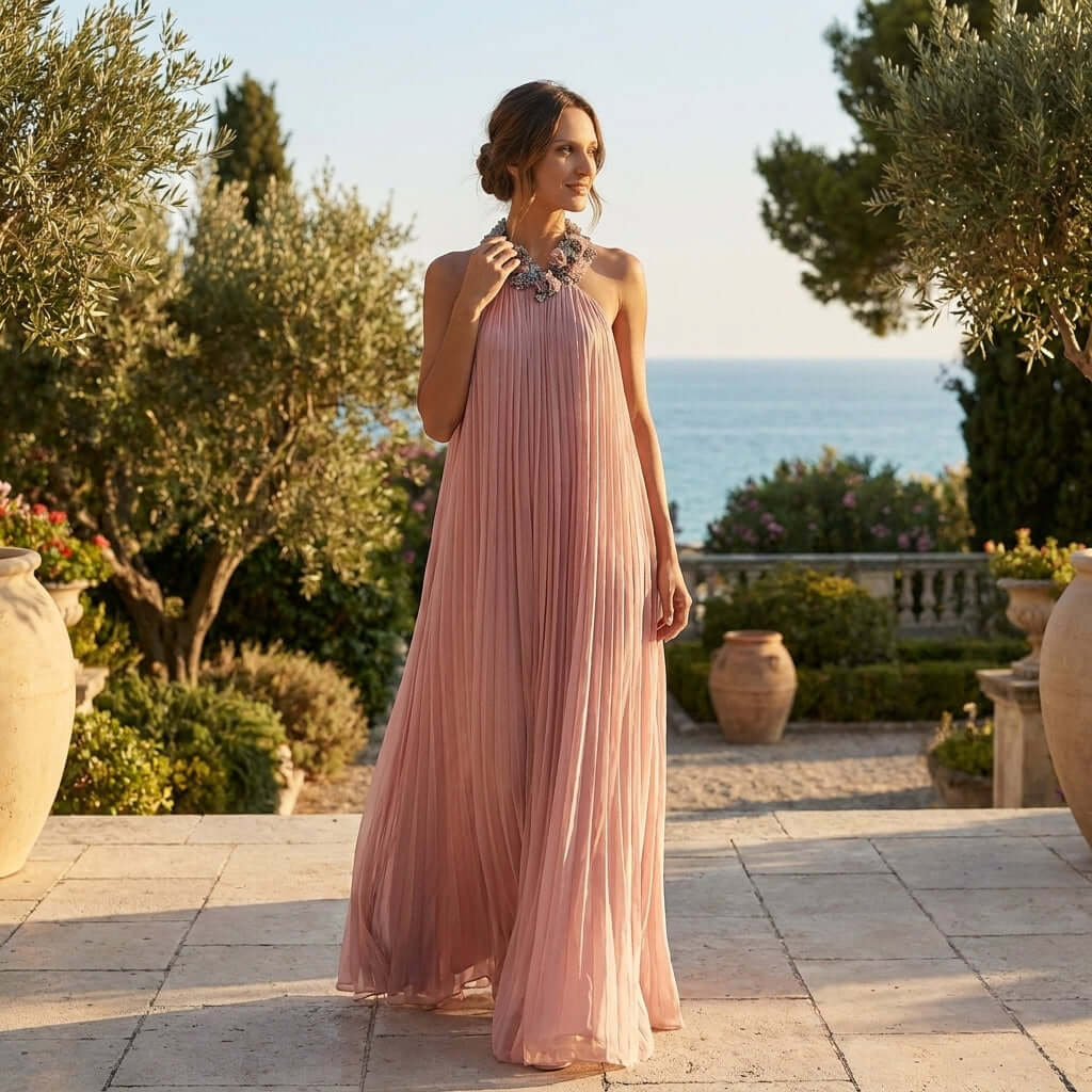 The Rozanne Halter Neck Maxi Dress with Beaded Collar by Eve Couture radiates sophistication in a picturesque garden setting. This luxurious couture dress is hand crafted in London, perfect for glamorous summer events, evening wear, and as a chic birthday or bridesmaid dress, ensuring a statement of elegance.