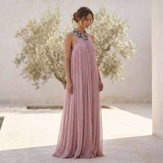 The Rozanne Halter Neck Maxi Dress with Beaded Collar by Eve Couture showcases a soft dusty pink silk fabric, elegantly draping for a stunning silhouette, perfect for special occasions. This luxury summer dress is hand made in London and embodies glamour as a designer cocktail dress for parties, weddings, or red carpet events. Ideal for moments that deserve opulence, it radiates sophistication as a contemporary maxi evening dress.