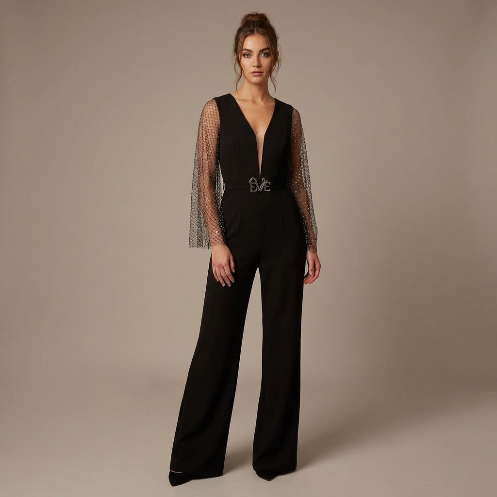 Female model elegantly poses in the Anemone Evening Jumpsuit by Eve Couture London, showcasing its daring V-neck and glamorous rhinestone sleeves. This dressy black luxury jumpsuit embodies the essence of couture, making it an exceptional option for parties and upscale gatherings, tailored to those who appreciate designer elegance.