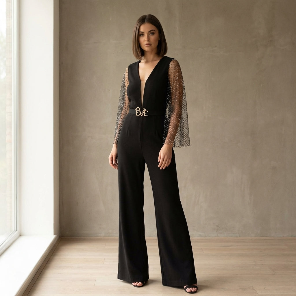 Model showcasing the Anemone Evening Jumpsuit by Eve Couture London, featuring flowy rhinestone mesh sleeves, in a pose that highlights the luxurious black design. This Black luxury Jumpsuit is perfect for elegant occasions, exuding couture charm that makes it an ideal choice for a red carpet look. Hand made in London, this designer evening jumpsuit is a staple of high-end fashion.