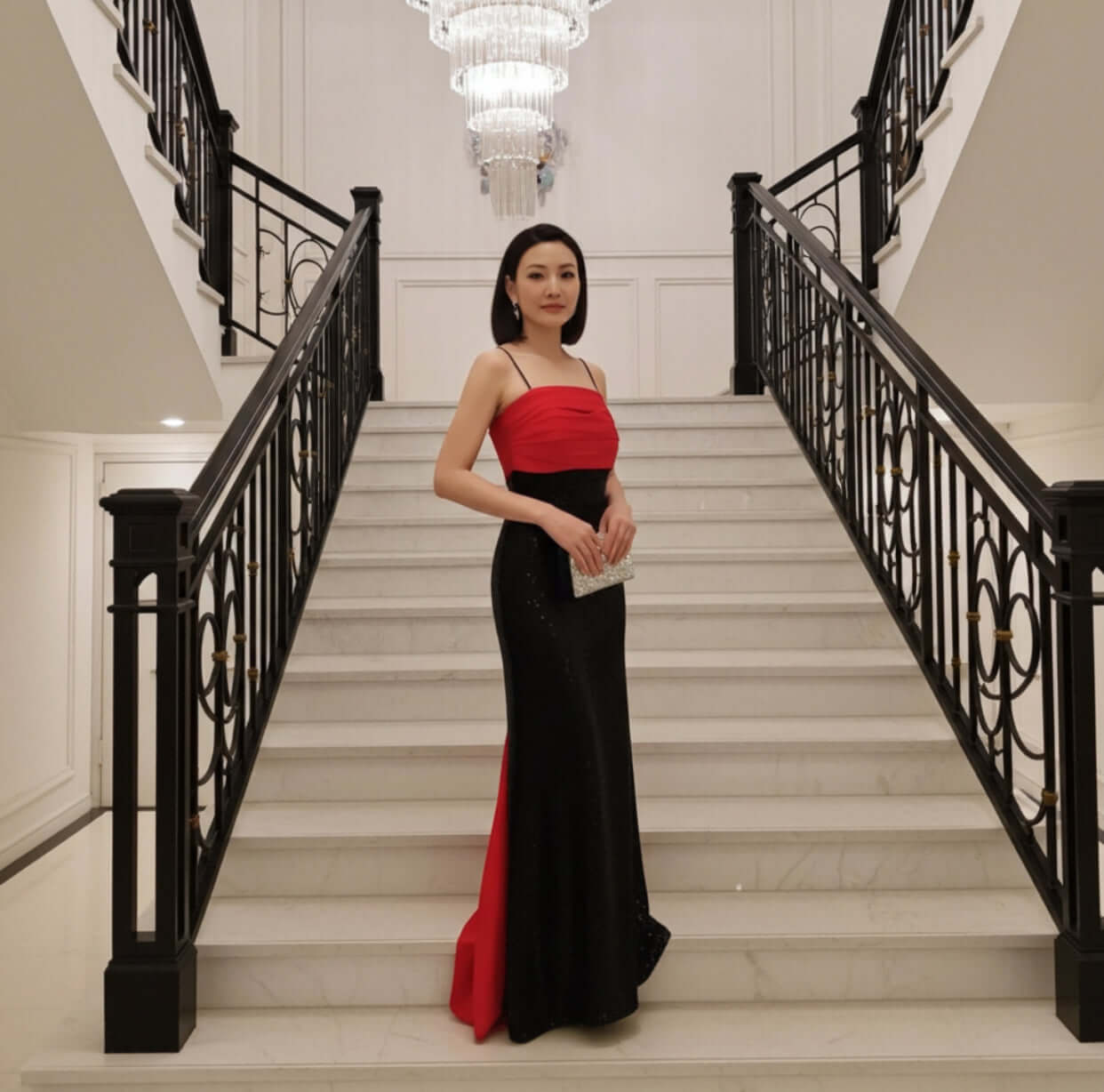 A graceful woman poses in the Amarine Evening Gown by Eve Couture on a grand staircase, the perfect representation of refined beauty in a luxury dress, striking the essence of couture elegance.