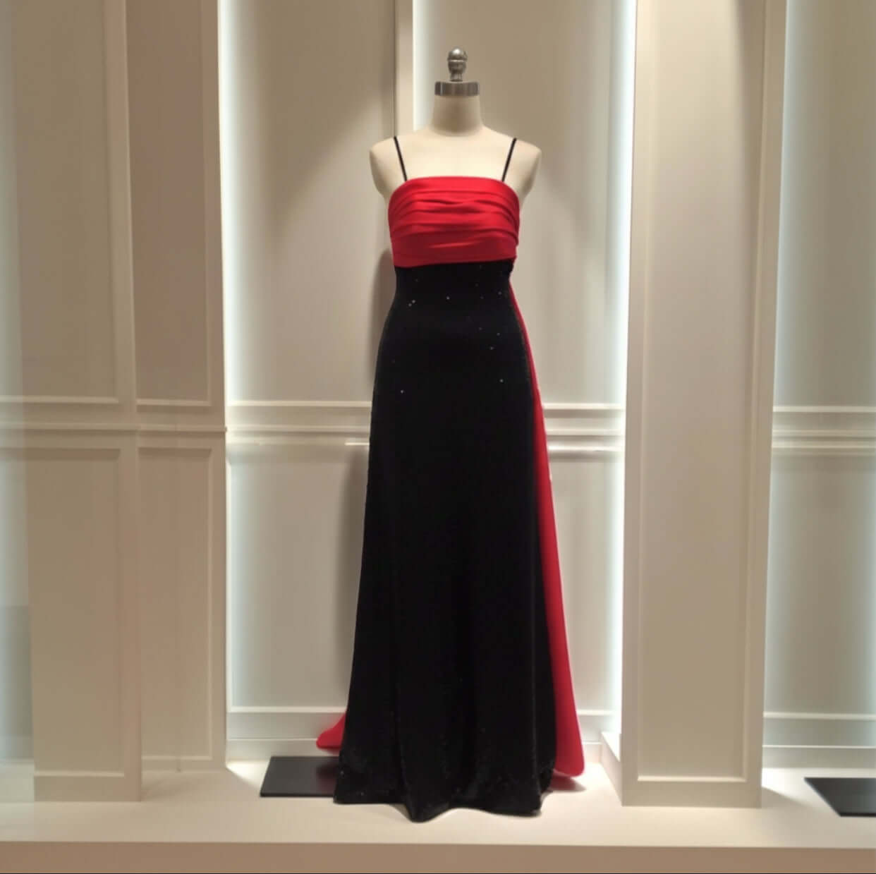 The Amarine Evening Gown by Eve Couture displayed elegantly on a mannequin, showcasing its luxurious design with black sequins and red silk, representing sophistication in evening wear and the allure of a couture dress.